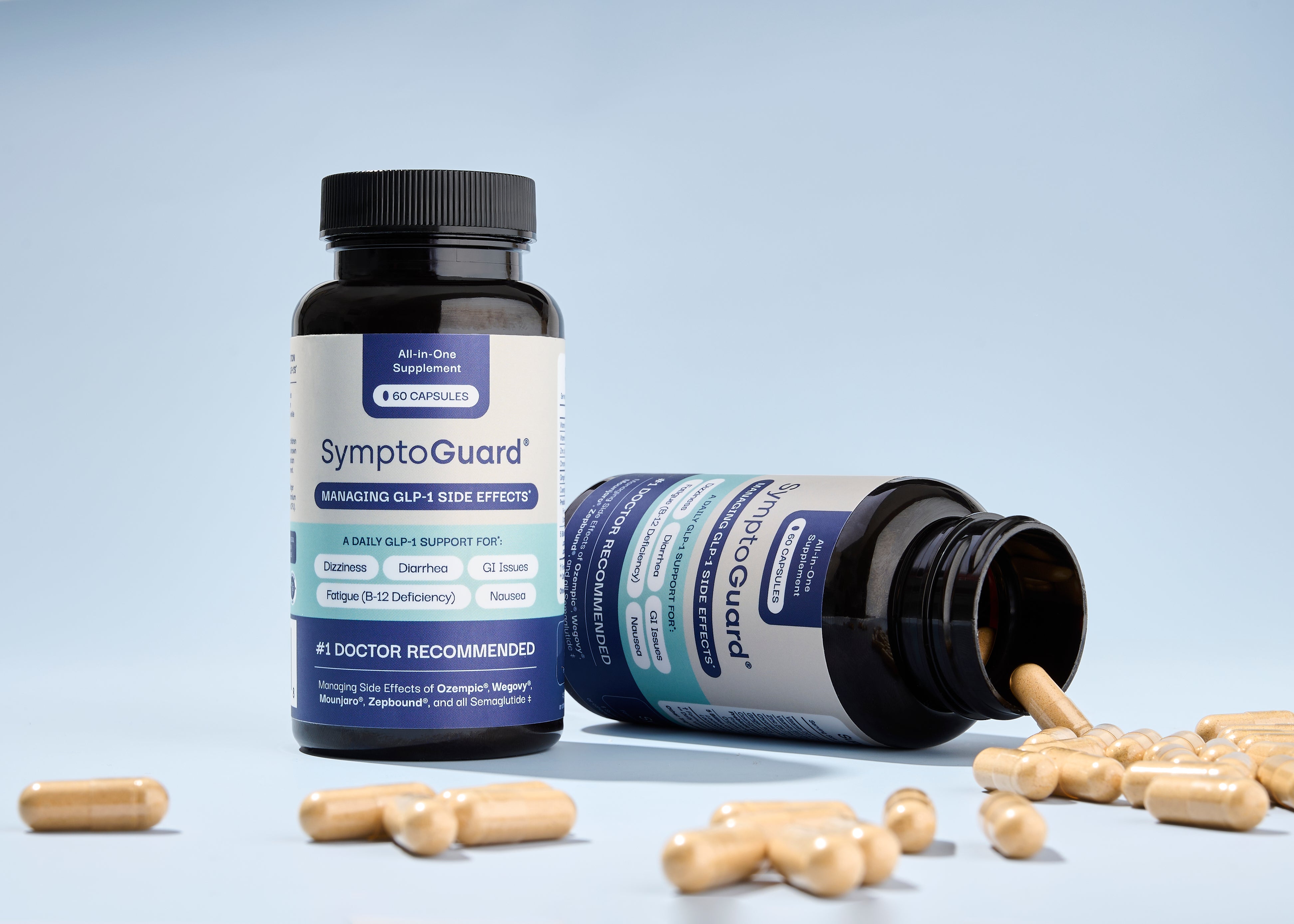 Two bottles of Symptoguard with one of them knocked over with pills spilling out in front of a light blue background.